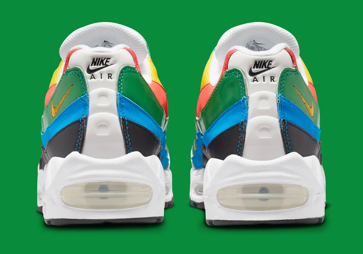 Nike Air Max 95 Olympic 2026 avec tige en mesh, cuir synthétique et suède blanc et bleu, détails Metallic Gold, unités Max Air visibles et semelle extérieure en caoutchouc vue de profil. 