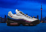 Nike Air Max 95 Toronto blanche, grise, rouge et bleue avec panneaux multicouches, Swoosh rouge et unités Max Air visibles.