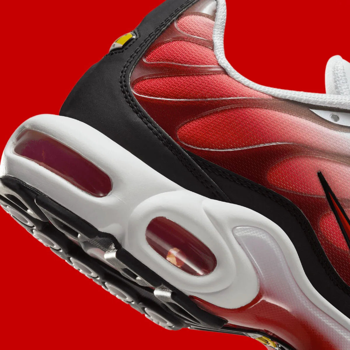 Vue zoomée sur les détails arrières de la Nike Air Max Plus White Black University Red blanche et rouge avec dégradé sur mesh, cage TPU, détails noirs et amorti Tuned Air visible.