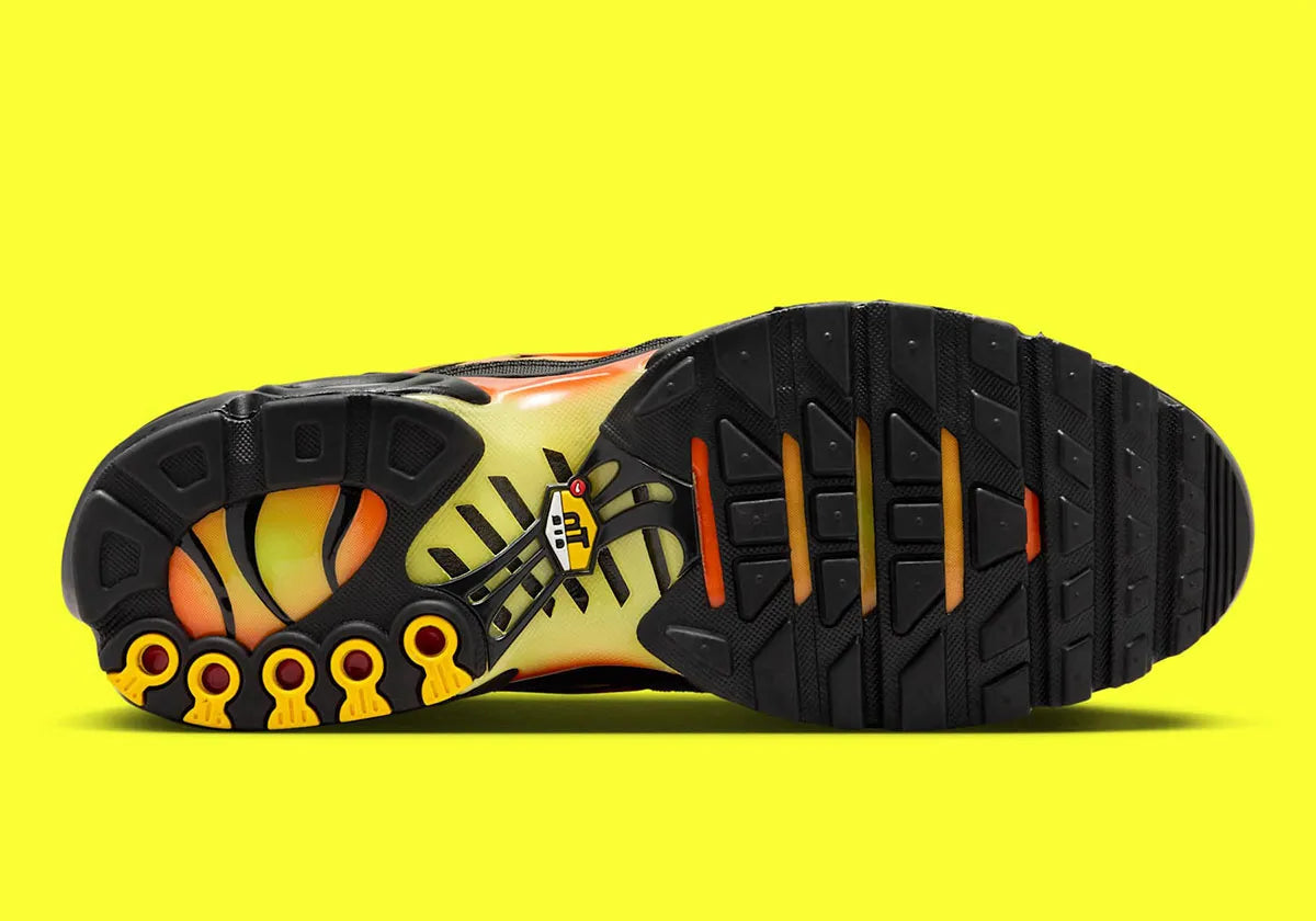 Nike Air Max Plus Sunrise noire avec cage dégradée jaune fluorescent et orange, tige en mesh et unités Nike Air visibles vue de dessous. 