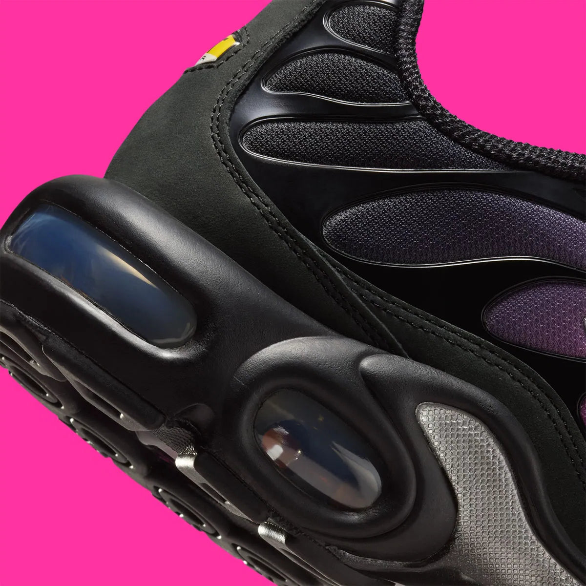 Vue zoomée sur les détails arrières de la Nike Air Max Plus Black Peony noire avec dégradé rose et violet, Swoosh argenté, cage TPU et détails cristallisés sur la languette.