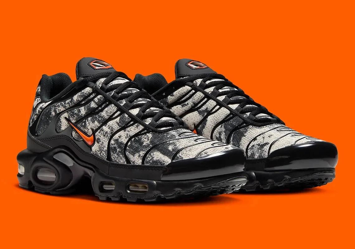 Sneakers Nike Air Max Plus noires camouflage avec accents Safety Orange en mesh technique et amorti Tuned Air visible

