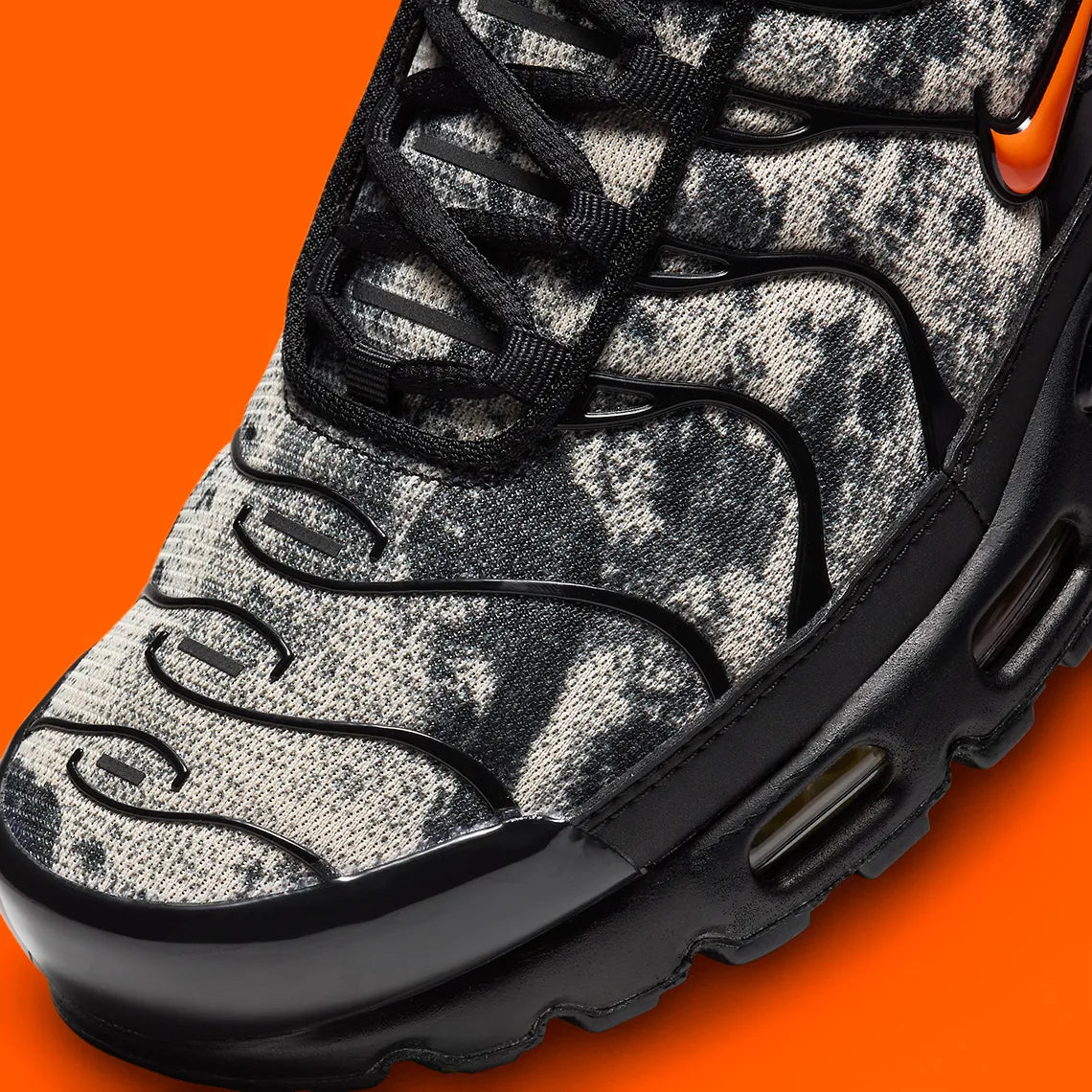 Sneakers Nike Air Max Plus noires camouflage avec accents Safety Orange en mesh technique et amorti Tuned Air visible

