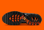 Sneakers Nike Air Max Plus noires camouflage avec accents Safety Orange en mesh technique et amorti Tuned Air visible
