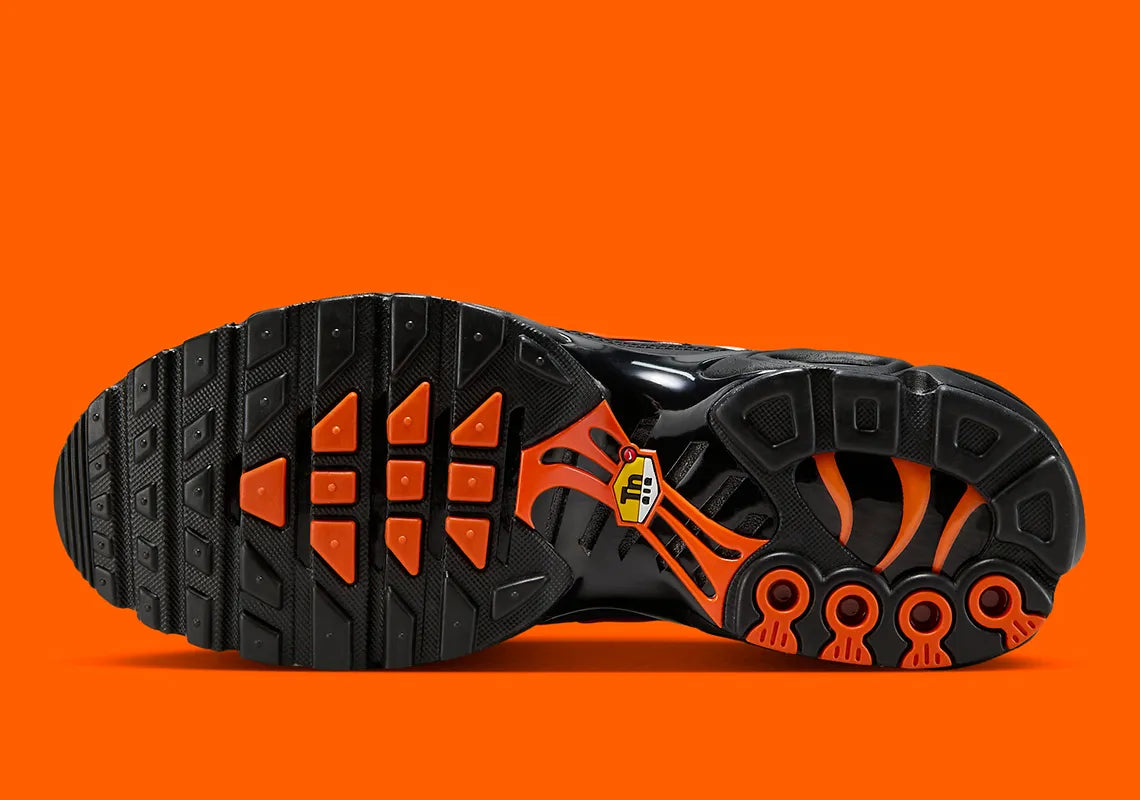 Sneakers Nike Air Max Plus noires camouflage avec accents Safety Orange en mesh technique et amorti Tuned Air visible
