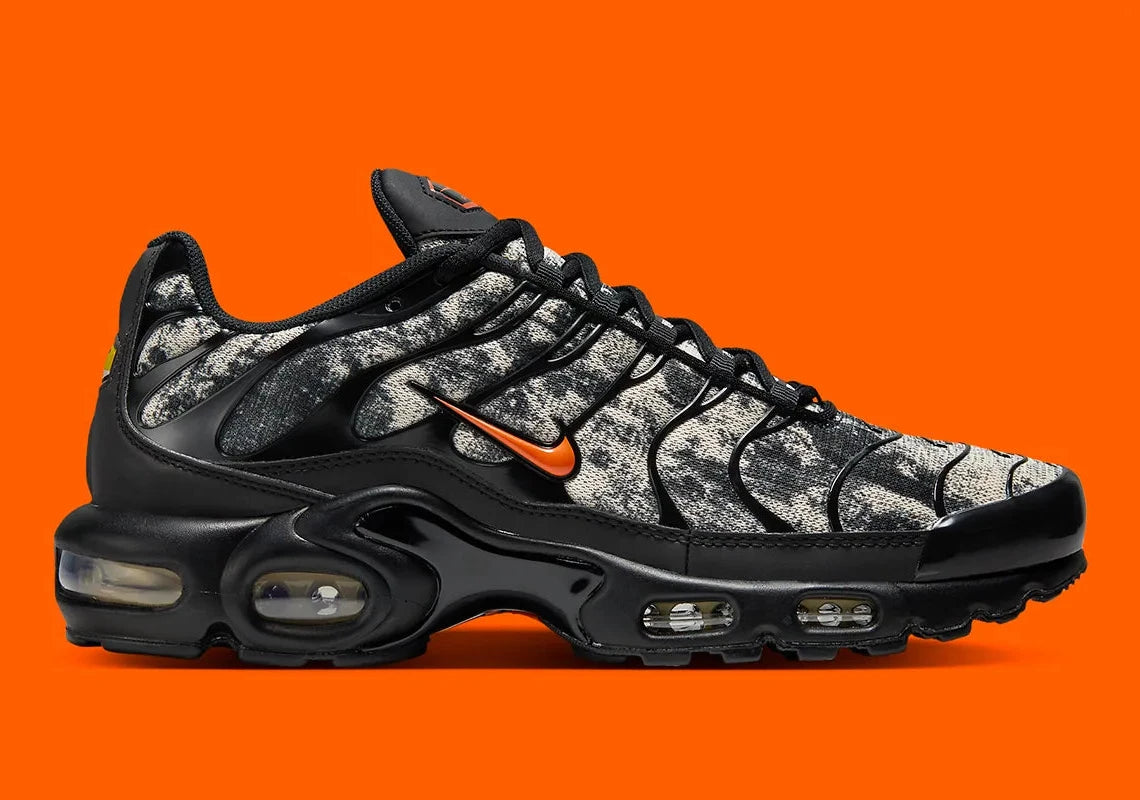 Sneakers Nike Air Max Plus noires camouflage avec accents Safety Orange en mesh technique et amorti Tuned Air visible
