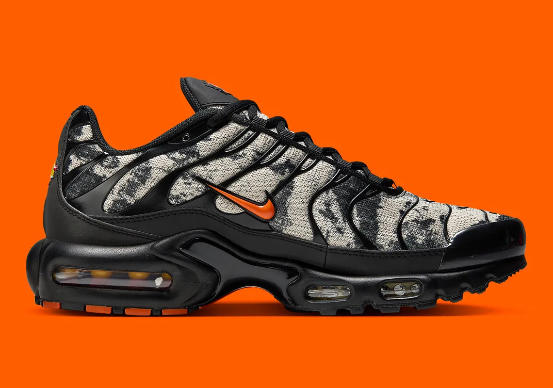 Sneakers Nike Air Max Plus noires camouflage avec accents Safety Orange en mesh technique et amorti Tuned Air visible
