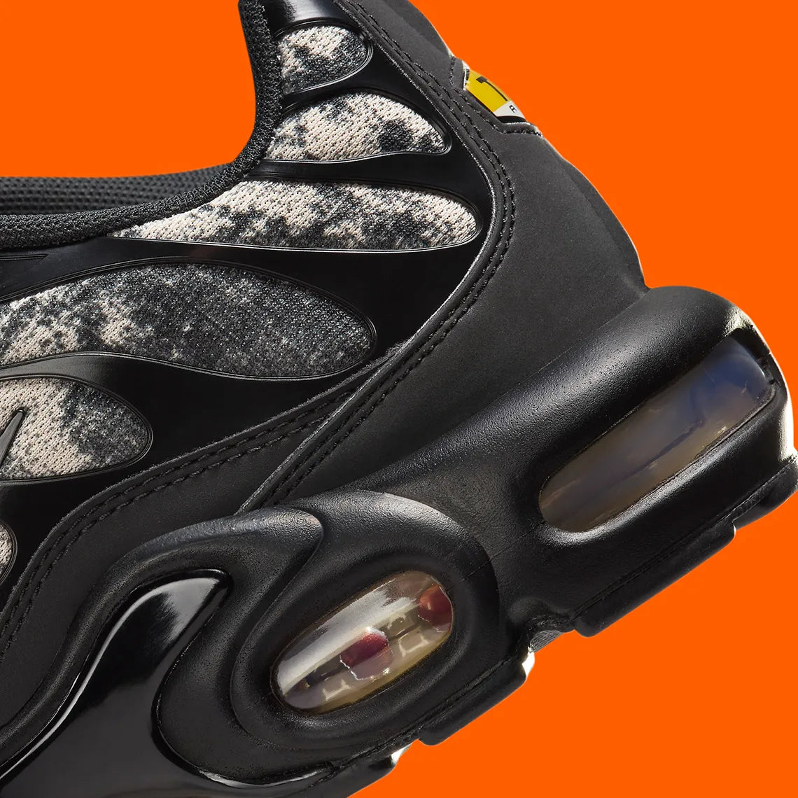 Sneakers Nike Air Max Plus noires camouflage avec accents Safety Orange en mesh technique et amorti Tuned Air visible

