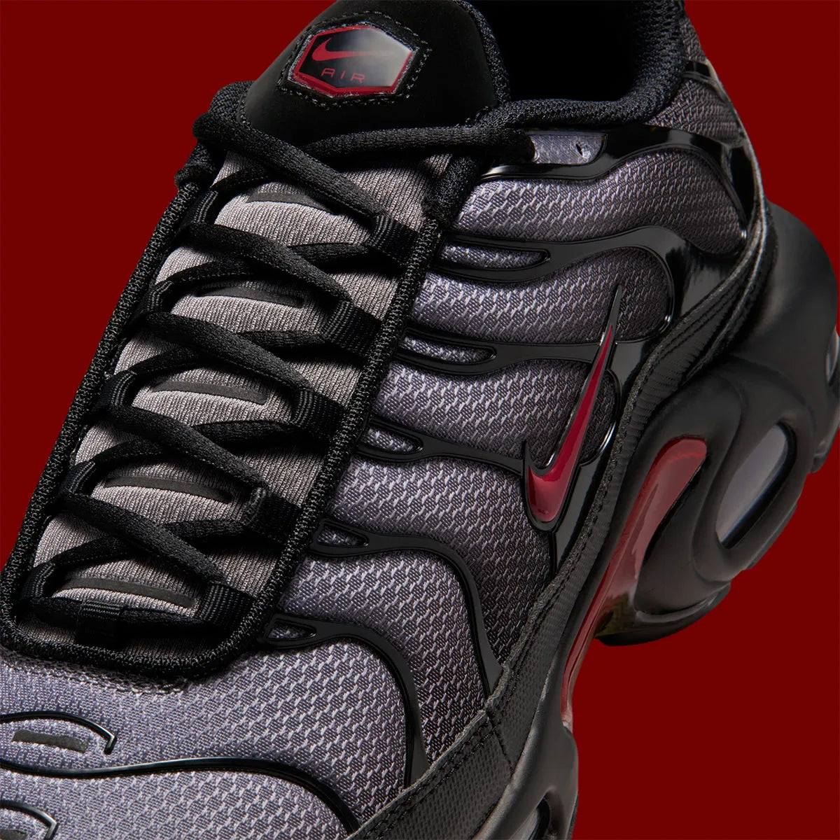 Nike Air Max Plus Black Pencil Point Team Crimson noire avec détails rouges Team Crimson, renforts ondulés et unités Air visibles.