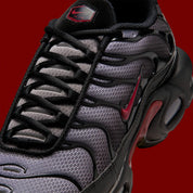 Nike Air Max Plus Black Pencil Point Team Crimson noire avec détails rouges Team Crimson, renforts ondulés et unités Air visibles.