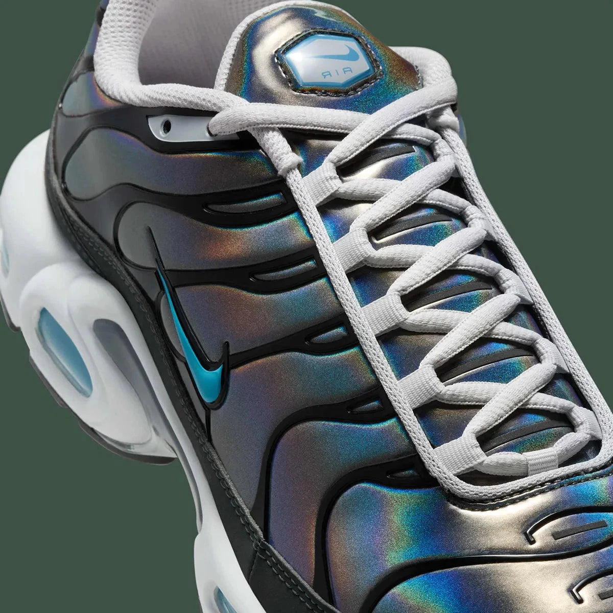 Vue zoomée sur les détails latéraux de la Nike Air Max Plus Iridescent noire avec tige aux reflets violet, bleu, vert et rose, cage noire et unités Air visibles.