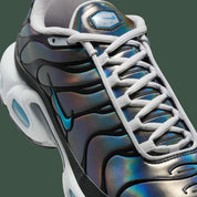 Vue zoomée sur les détails latéraux de la Nike Air Max Plus Iridescent noire avec tige aux reflets violet, bleu, vert et rose, cage noire et unités Air visibles.