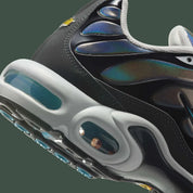 Vue zoomée sur les détails arrières de la Nike Air Max Plus Iridescent noire avec tige aux reflets violet, bleu, vert et rose, cage noire et unités Air visibles.