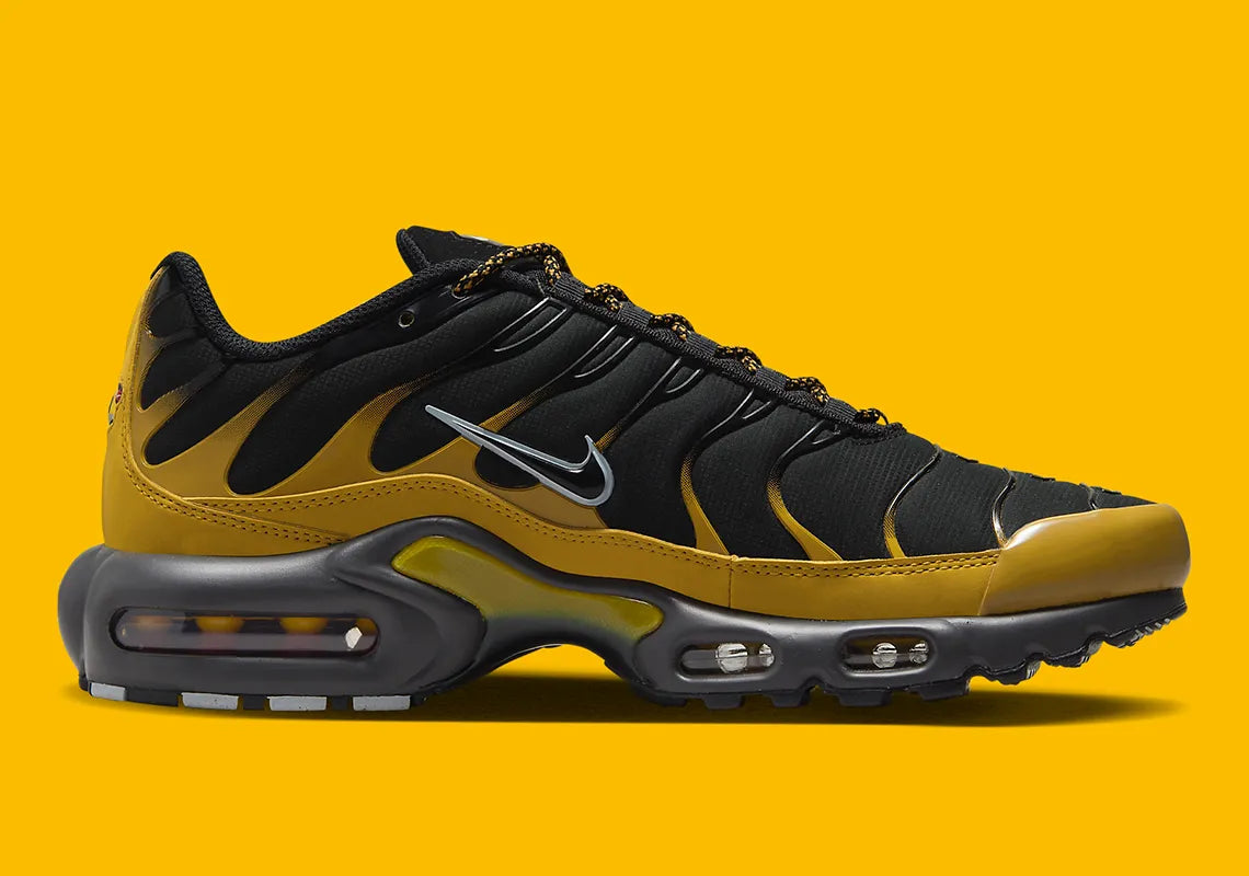 Nike Air Max Plus Bronzine beige et taupe avec tige en mesh, détails noirs, renforts ondulés et unités Air visibles.