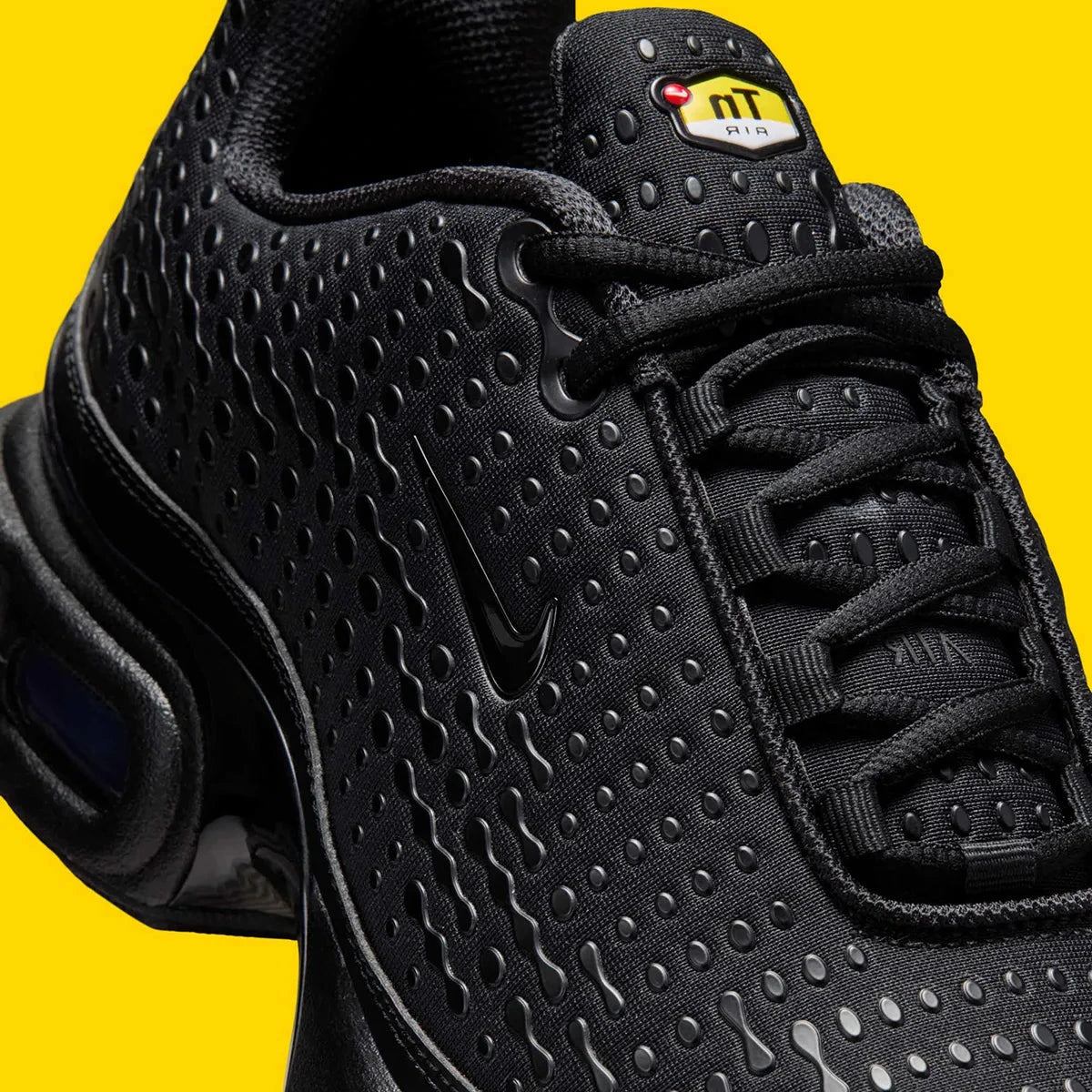 Vue zoomée sur les détails latéraux de la Nike Air Max Plus 7 Black noire et anthracite avec tige en mesh, renforts ondulés et unités Nike Air visibles. 