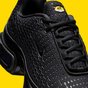 Vue zoomée sur les détails latéraux de la Nike Air Max Plus 7 Black noire et anthracite avec tige en mesh, renforts ondulés et unités Nike Air visibles. 