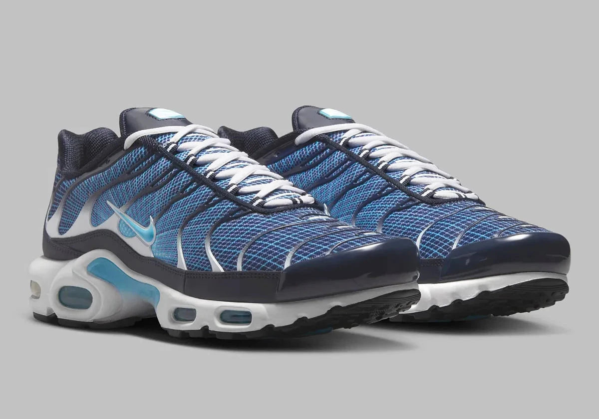 Image de la Nike Air Max Plus Dark Obsidian, sneaker en mesh et overlay bleu obsidien, avec accents Blue Chill, cages TPU ondulées, unités d’amorti Tuned Air visibles, silhouette TN classique revisitée. Vue de coter