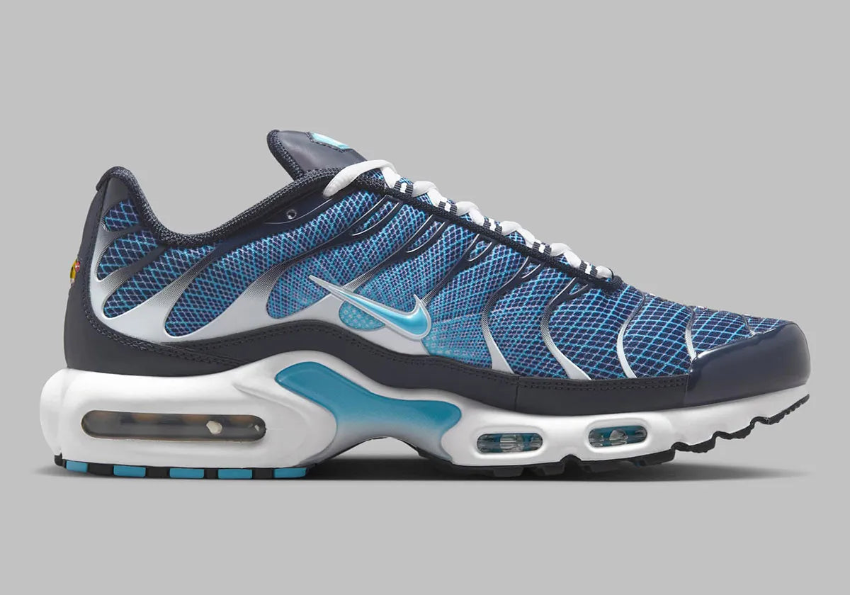 Image de la Nike Air Max Plus Dark Obsidian, sneaker en mesh et overlay bleu obsidien, avec accents Blue Chill, cages TPU ondulées, unités d’amorti Tuned Air visibles, silhouette TN classique revisitée. Vue de coter