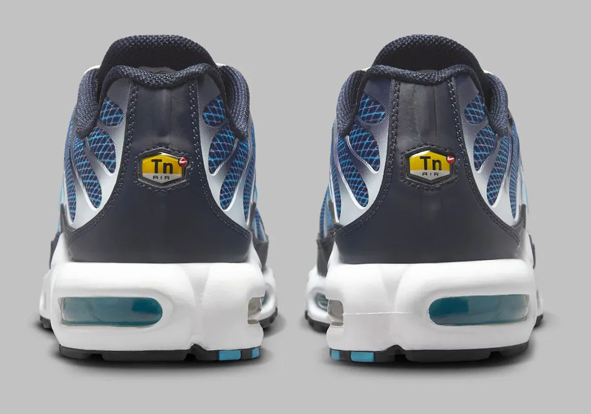 Image de la Nike Air Max Plus Dark Obsidian, sneaker en mesh et overlay bleu obsidien, avec accents Blue Chill, cages TPU ondulées, unités d’amorti Tuned Air visibles, silhouette TN classique revisitée. Vue arrière 