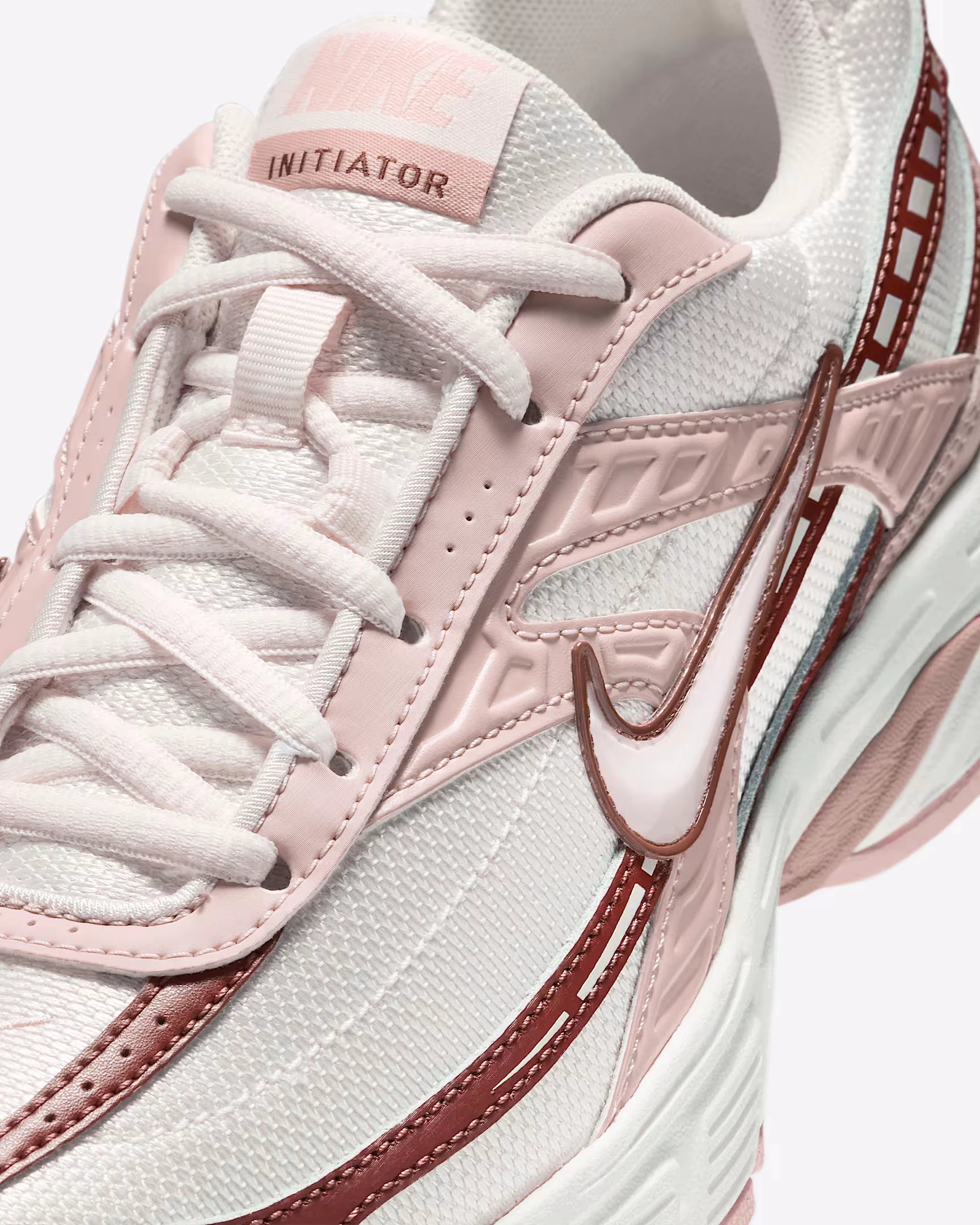 Vue zoomée sur les détails latéraux de la Nike Initiator Red Sepia Echo Pink IB4339-002 avec tige crème et beige, accents rose et brun et silhouette rétro-running multicouche.
