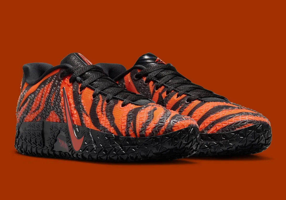 Nike Ja 3 Animal Pack Tiger avec tige textile aux tons chauds et motifs rayés, renforts structurés, amorti réactif et semelle en caoutchouc adhérente.