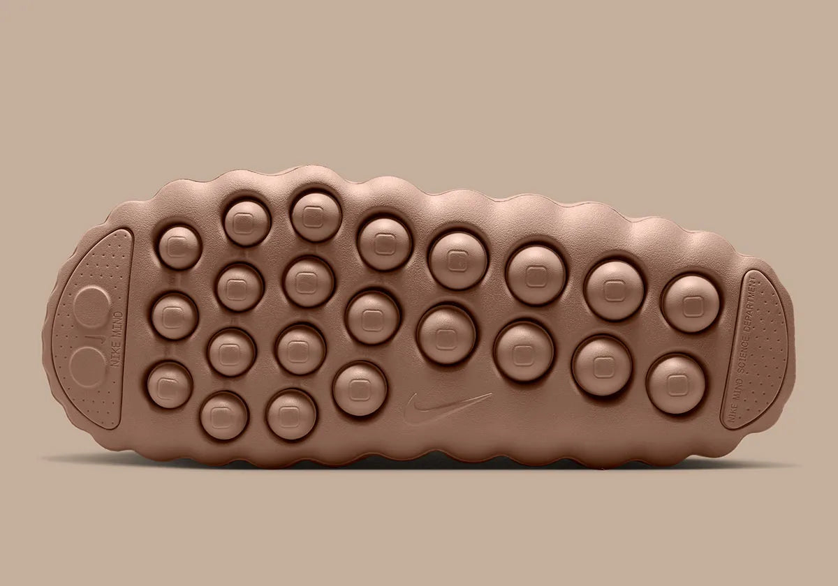 Nike Mind 001 Slide Rattan avec construction mule beige naturel, empeigne technique respirante et semelle sensorielle à 22 points de pression articulés.