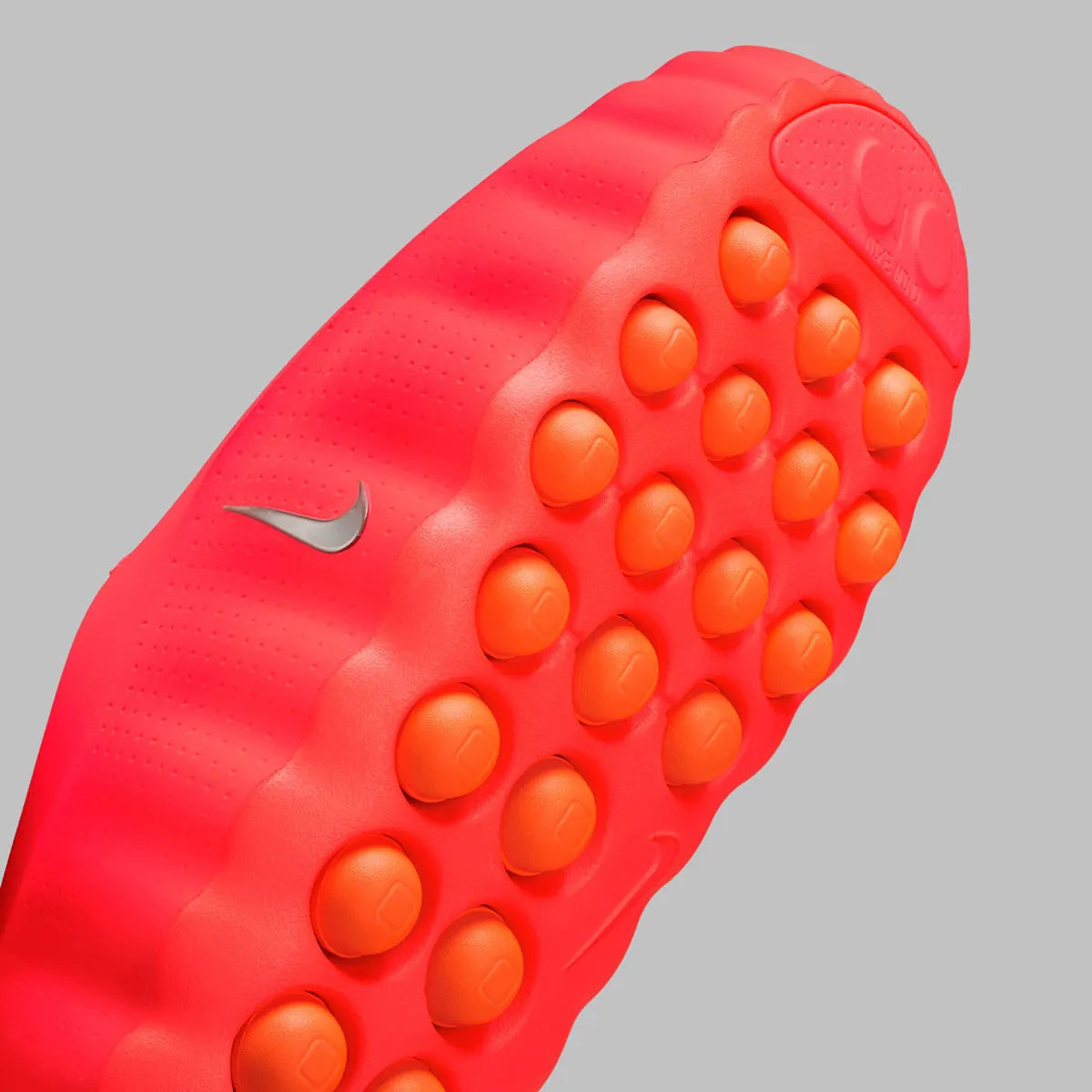 Slides Nike Mind 001 Solar Red rouges en mousse technique avec nœuds sensoriels sous la semelle et design futuriste, vue zoomée sur les détails en dessous de la chaussure. 