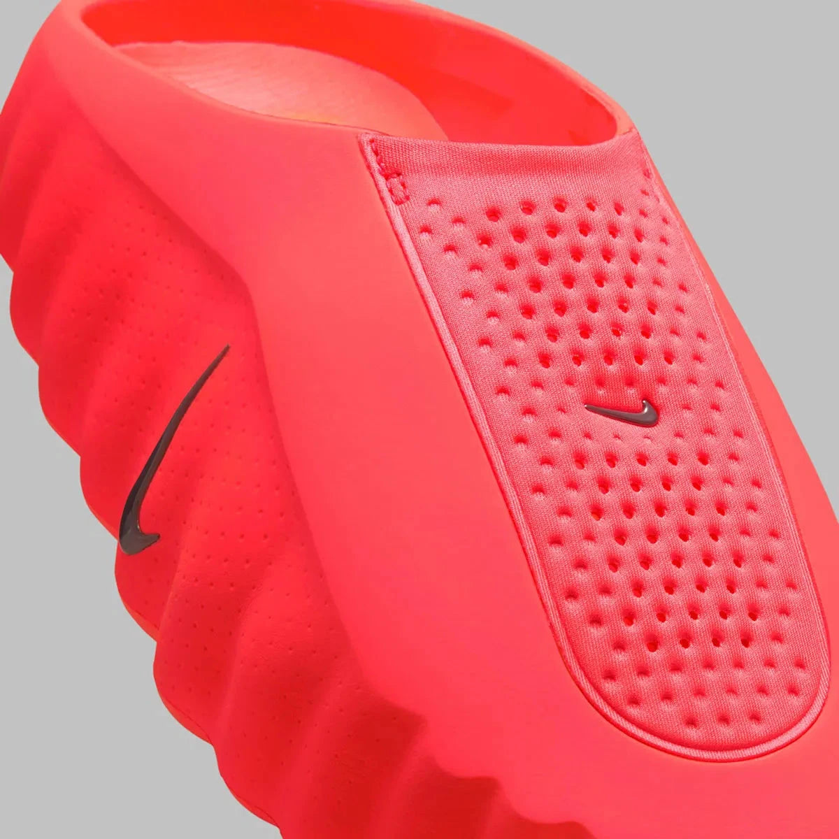 Slides Nike Mind 001 Solar Red rouges en mousse technique avec nœuds sensoriels sous la semelle et design futuriste, vue zoomée sur l'avant de la paire. 