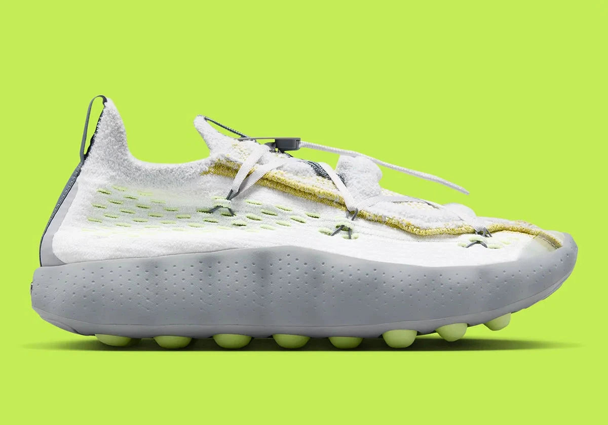 Nike Mind 002 Flyknit White Dark Grey Volt avec tige en Flyknit blanc et gris foncé, accents Volt fluorescents et semelle moderne offrant confort et adhérence.