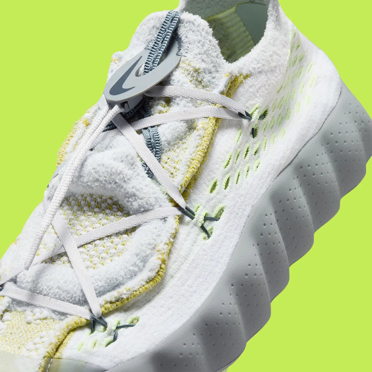 Nike Mind 002 Flyknit White Dark Grey Volt avec tige en Flyknit blanc et gris foncé, accents Volt fluorescents et semelle moderne offrant confort et adhérence.