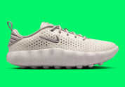Nike Mind 002 Phantom College Grey avec tige en textile technique clair, détails gris, construction enveloppante et semelle sensorielle avec amorti en mousse souple.