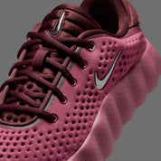 Nike Mind 002 Pink Smoke Mystic Dates avec tige en textile technique rose fumé, détails aux nuances terreuses et semelle moderne offrant confort et adhérence.