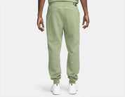 Nike x NOCTA Fleece CS Sweatpant Oil Green/Light Liquid Lime, pantalon fleece vert avec coupe ample, poches zippées et détails réfléchissants NOCTA.