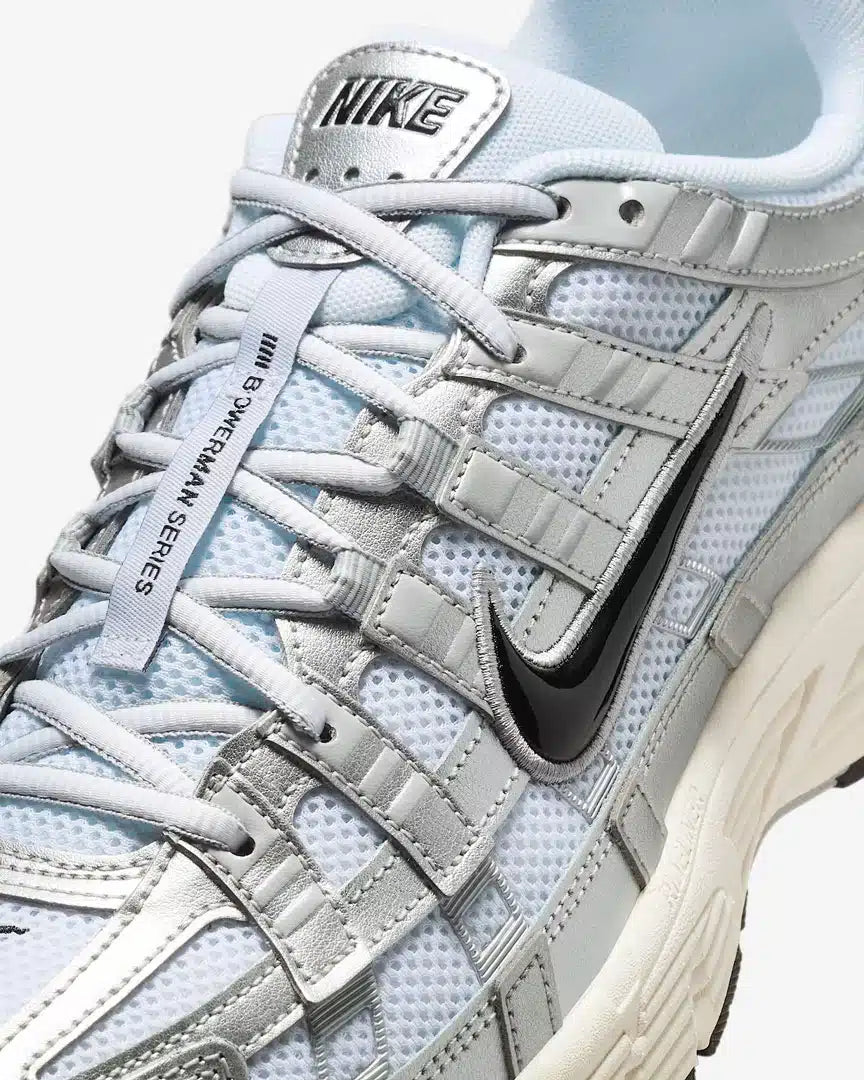 La Nike P-6000 White Metallic Silver Flat Silver Black en mesh blanc et cuir synthétique argenté avec semelle caoutchouc, design rétro-running.
