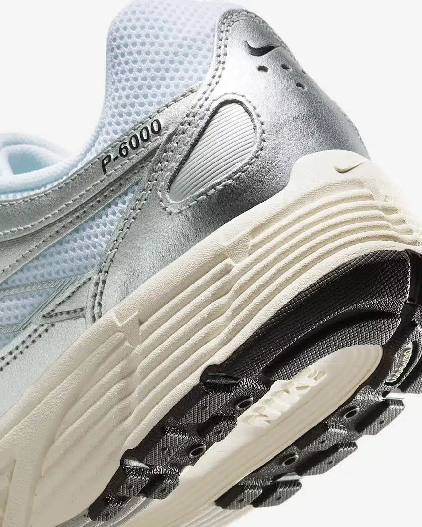 La Nike P-6000 White Metallic Silver Flat Silver Black en mesh blanc et cuir synthétique argenté avec semelle caoutchouc, design rétro-running.