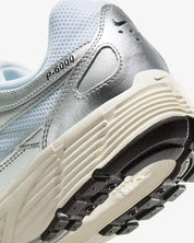 La Nike P-6000 White Metallic Silver Flat Silver Black en mesh blanc et cuir synthétique argenté avec semelle caoutchouc, design rétro-running.