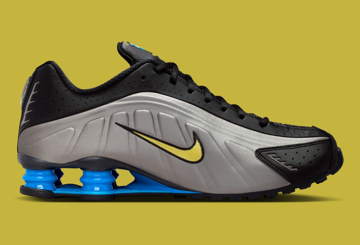 Nike Shox R4 Brazil avec tige en mesh noir et empiècements synthétiques, détails Canary et Light Photo Blue, amorti Nike Shox et semelle extérieure en caoutchouc.