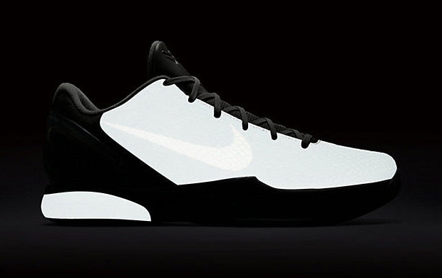 Image de la Nike Kobe 6 Black Mamba Collection Fade To Black, sneaker de basketball gris anthracite texturée en écaille de serpent, semelle Zoom Air et finitions dorées. Vue de profil dans le noir pour voir le glow de la paire.