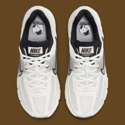 Image de la Nike Zoom Vomero 5 Phantom / Light Iron Ore, sneaker gris clair et blanc cassé en mesh et cuir, superpositions gris acier, semelle noire à amorti Zoom Air visible.