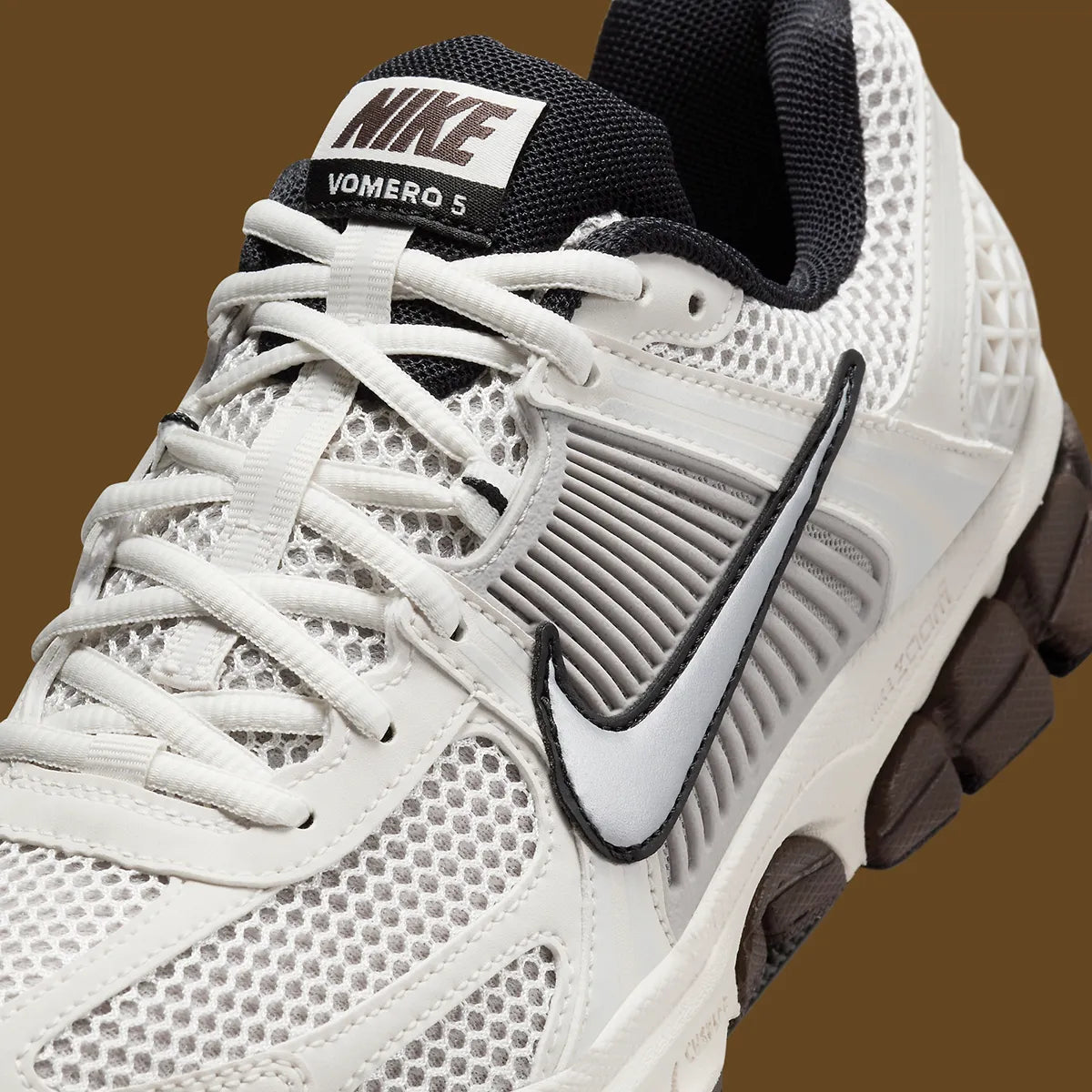  Image de la Nike Zoom Vomero 5 Phantom / Light Iron Ore, sneaker gris clair et blanc cassé en mesh et cuir, superpositions gris acier, semelle noire à amorti Zoom Air visible.