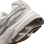 Vue zoomée sur les détails arrières de la Nike Initiator Phantom Light Bone Sail Mink Brown IB4339-001 avec tige crème et beige, détails bruns et silhouette rétro-running multicouche.