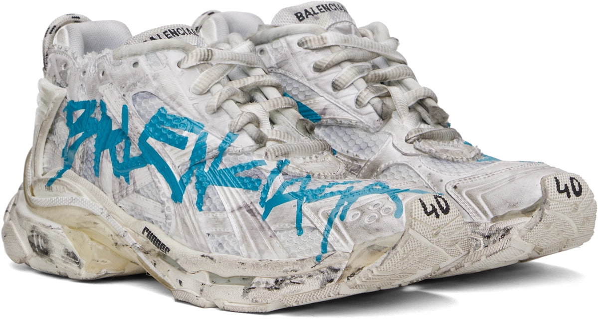 Balenciaga Runner Graffiti White Blue avec tige en mesh respirant, empiècements en cuir et matières synthétiques blanches et bleues, finitions graffiti et semelle épaisse en caoutchouc.