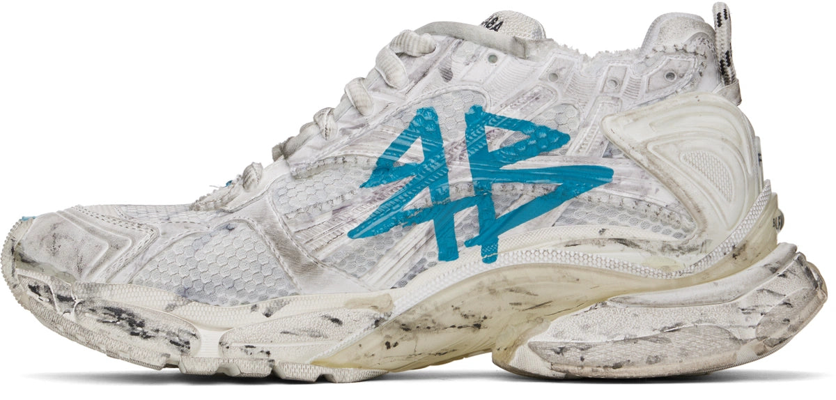 Balenciaga Runner Graffiti White Blue avec tige en mesh respirant, empiècements en cuir et matières synthétiques blanches et bleues, finitions graffiti et semelle épaisse en caoutchouc.