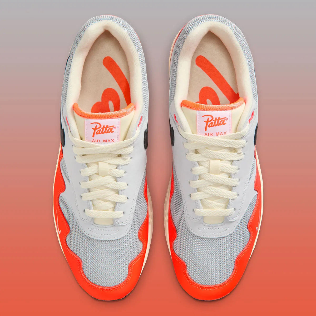 Sneakers Nike Air Max 1 Patta Waves Hyper Crimson Pure Platinum en mesh gris et cuir avec garde-boue ondulé orange et unité Air visible.