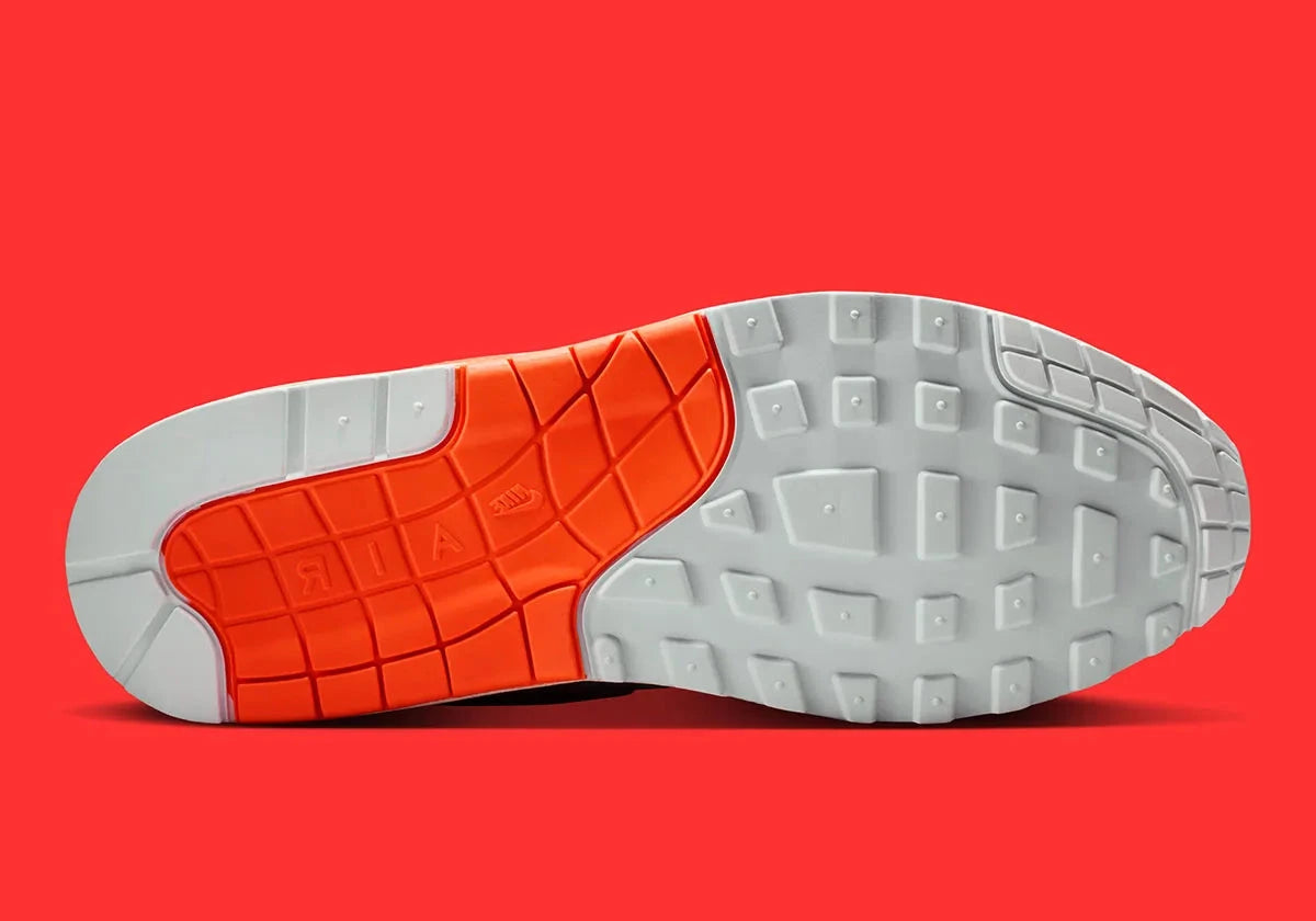 Vue sur la semelle de la Sneakers Nike Air Max 1 Patta Waves White Hyper Crimson en mesh blanc avec mudguard ondulé orange et unité Air visible.