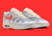 Sneakers Nike Air Max 1 Patta Waves White Hyper Crimson en mesh blanc avec mudguard ondulé orange et unité Air visible vue de 3/4 face. 