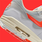 Vue sur les détails arrières de la Sneakers Nike Air Max 1 Patta Waves White Hyper Crimson en mesh blanc avec mudguard ondulé orange et unité Air visible.
