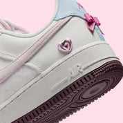 Sneakers Nike Air Force 1 Low Valentine's Day 2026 pour femme en cuir premium clair, avec détails roses et rouges, motifs exclusifs et amorti Nike Air encapsulé.Vue zoomer arrière 