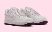 Sneakers Nike Air Force 1 Low Valentine's Day 2026 pour femme en cuir premium clair, avec détails roses et rouges, motifs exclusifs et amorti Nike Air encapsulé.Vue de profil