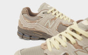 New Balance 2002R Protection Pack Brown en suède brun avec empiècements à bords bruts, semelle N-ergy et silhouette rétro-running.